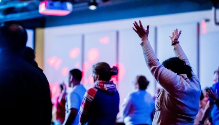 Pessoas louvando durante culto em igreja (Foto: Canva Pro)